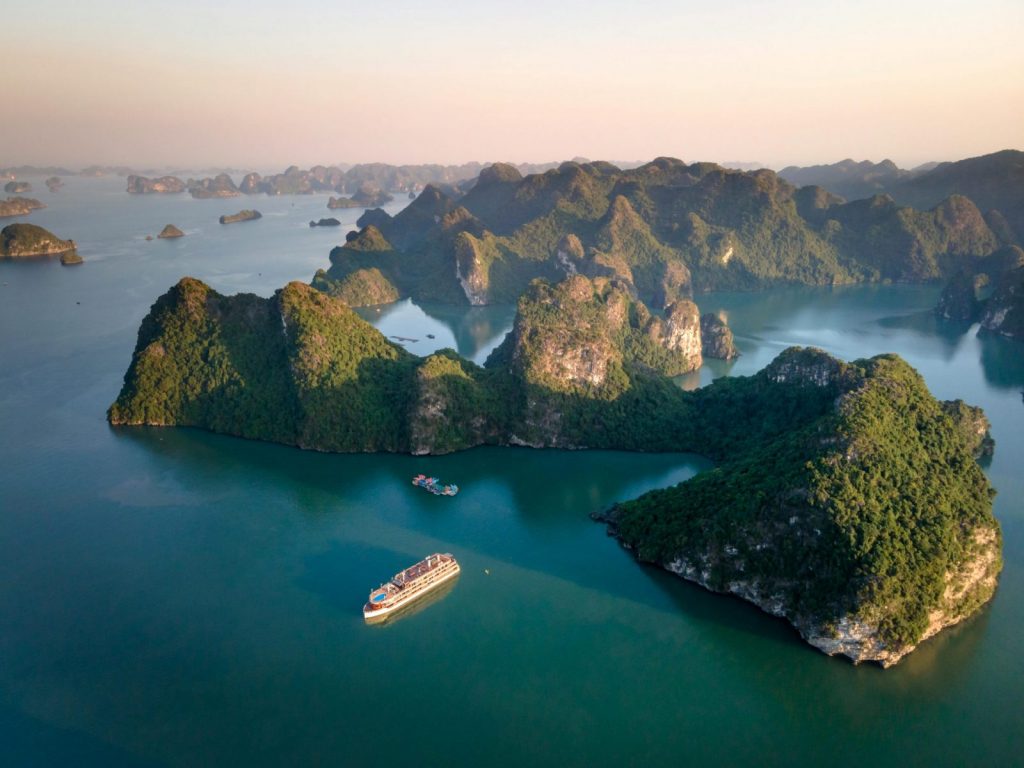 An aerial view showcasing the stunning limestone islands of Ha Long Bay at sunset.
