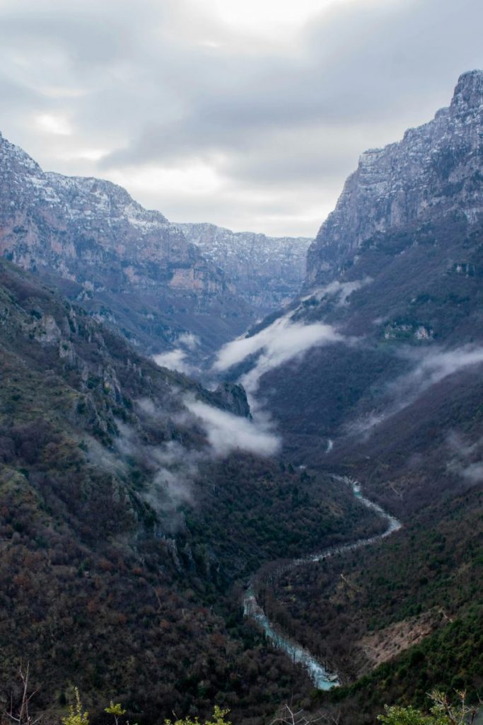 A dramatic view of Vikos Gorge with clouds and rugged mountains in Monodendri, Greece.