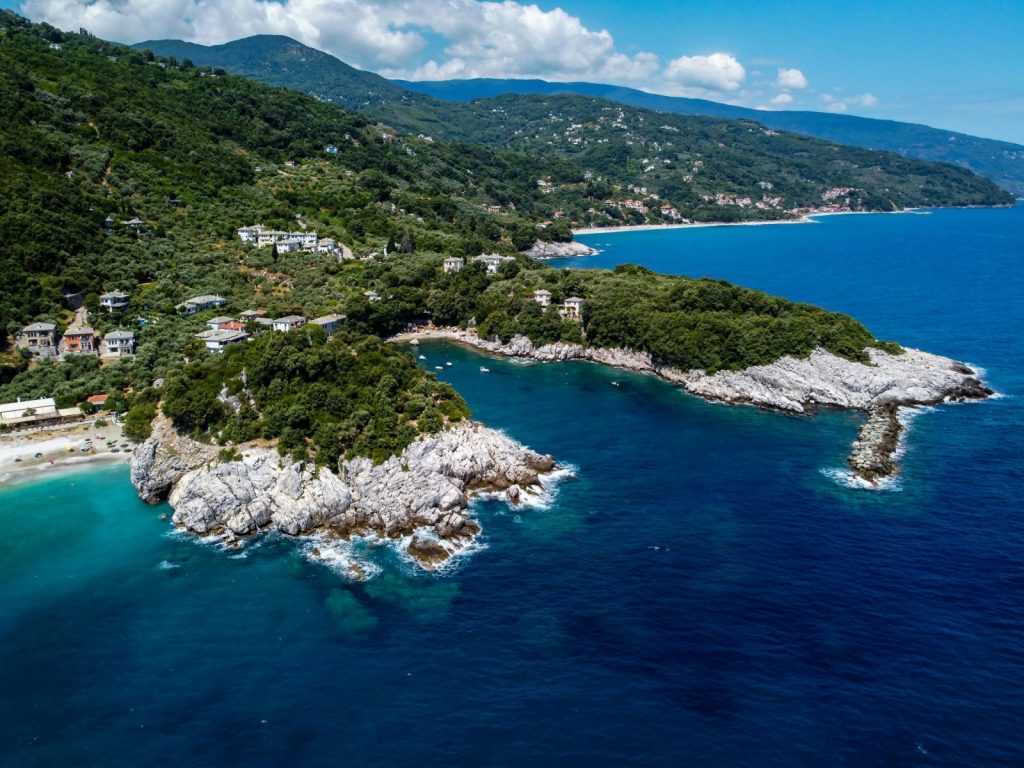 Stunning aerial view of a lush Greek coastline meeting the azure sea.