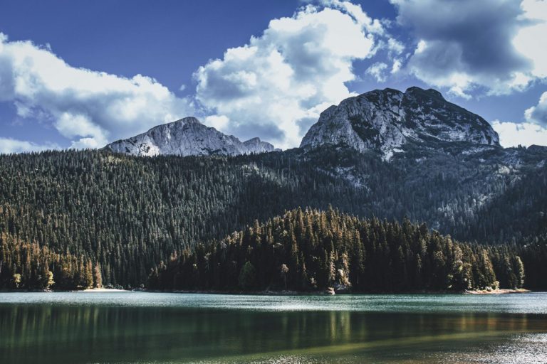 Idyllic landscape of Mount Durmitor with Black Lake in foreground under a bright sky.