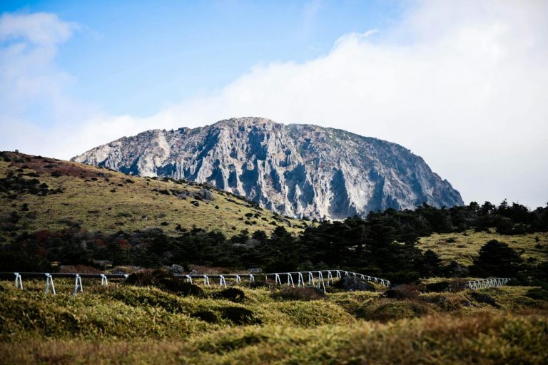 Breathtaking view of a mountain with lush hills and a fence under a clear sky.