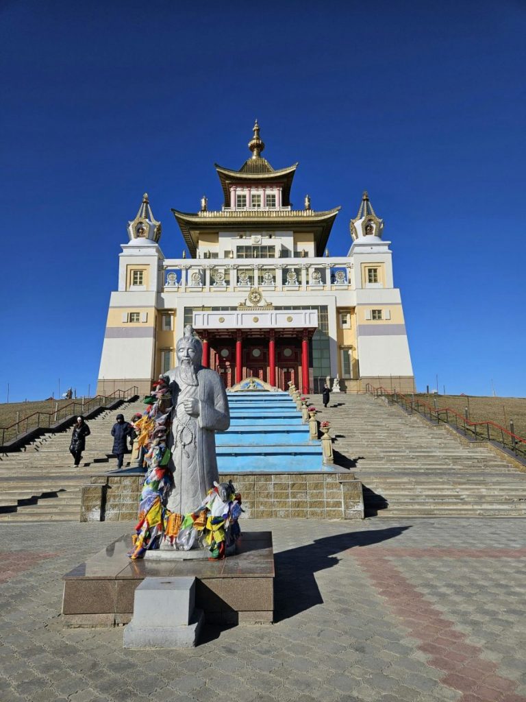 Buddhist temple with statue in front on a sunny day, highlighting its architecture.