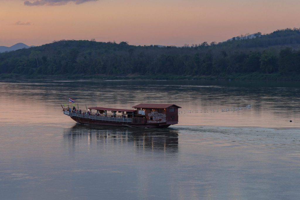 A tranquil evening view of a boat on the Mekong River at sunset in Chiang Khan, Thailand.