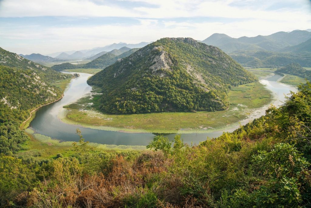 Breathtaking aerial view of Rijeka Crnojevića river bend in Montenegro with lush mountains.